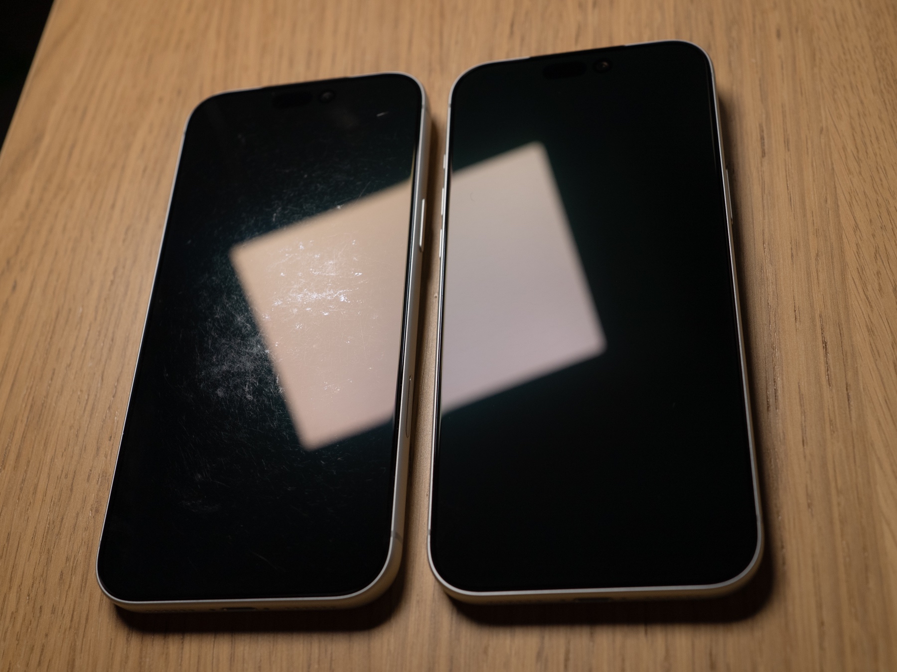 Two phones: worn screen protector coating on the left, like-new coating on the right
